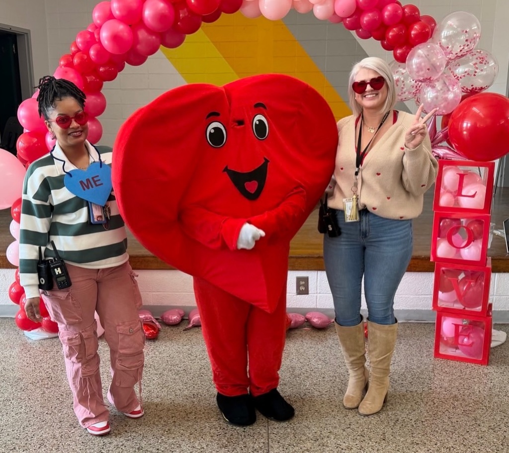 staff standing with heart character beneath balloon arch