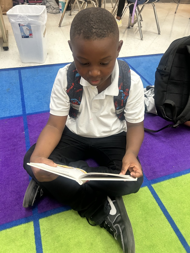 male student, reading on colorful rug with backpack on