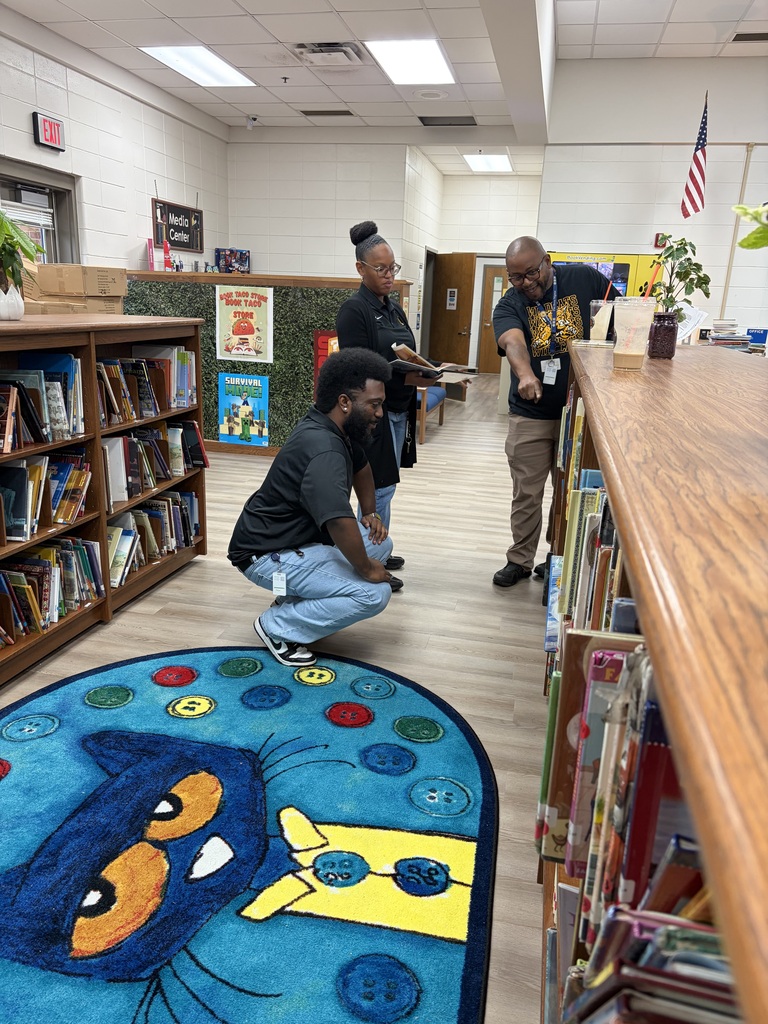 three teachers browsing in a library section over a large rug of Pete the Cat