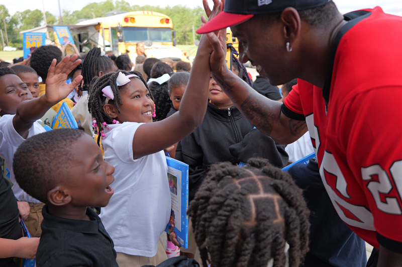 Malcolm high-fiving a student, both smiling