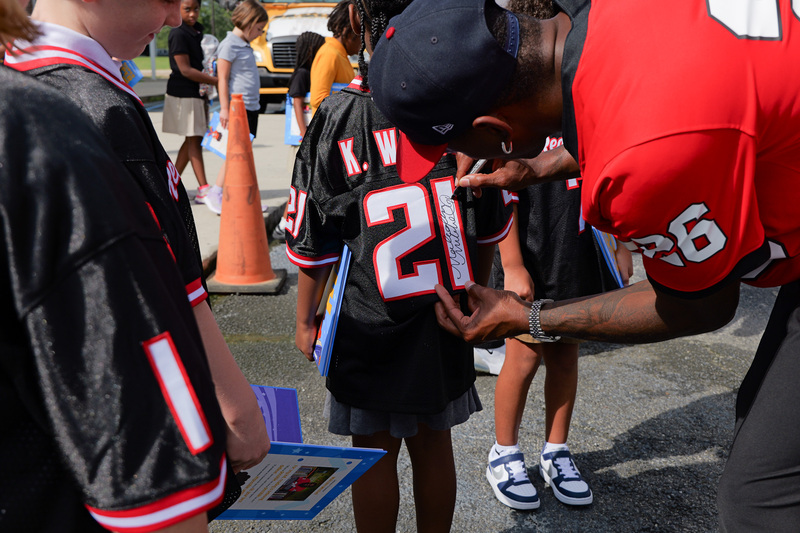 Malcolm signing a student's jersey with a sharpie