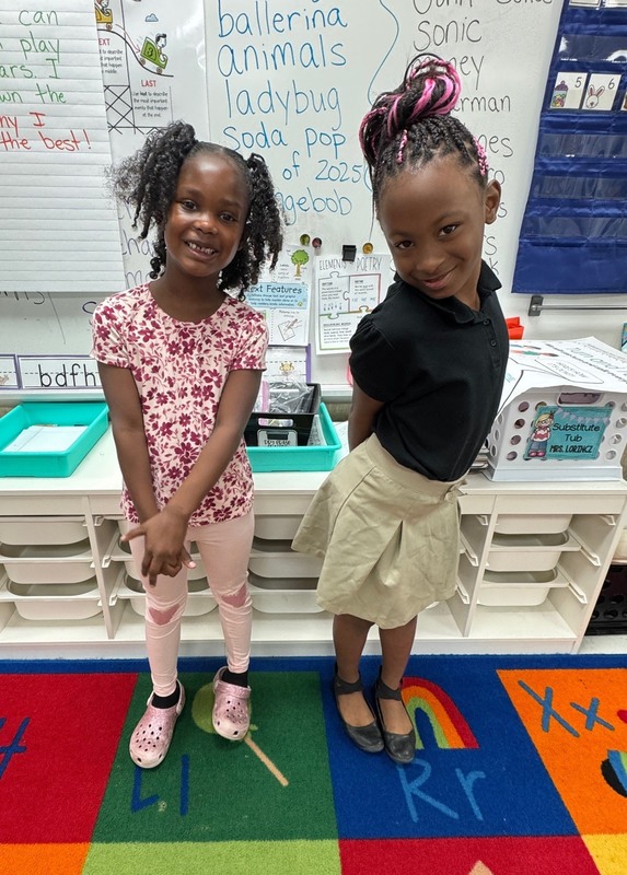 two students, standing and smiling