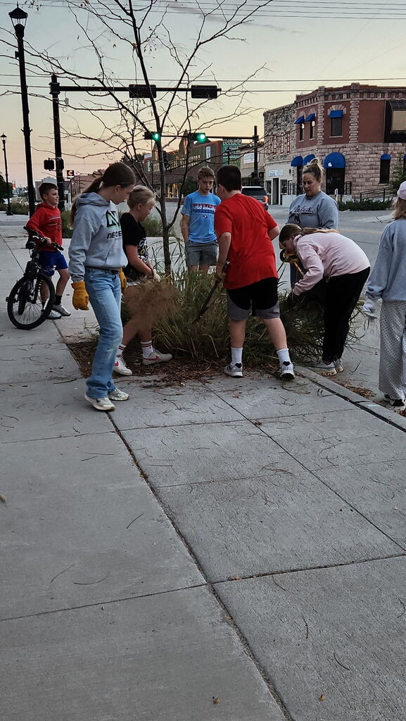 Students trimming bushes and pulling weeds from city streets.