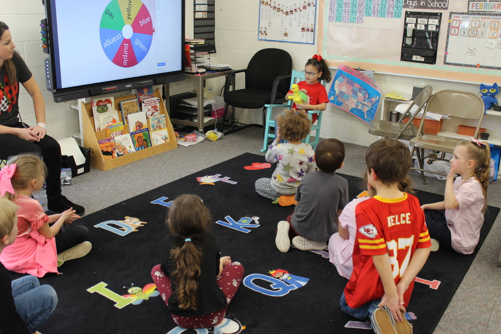 Girl reading to Grandparents & Classmates