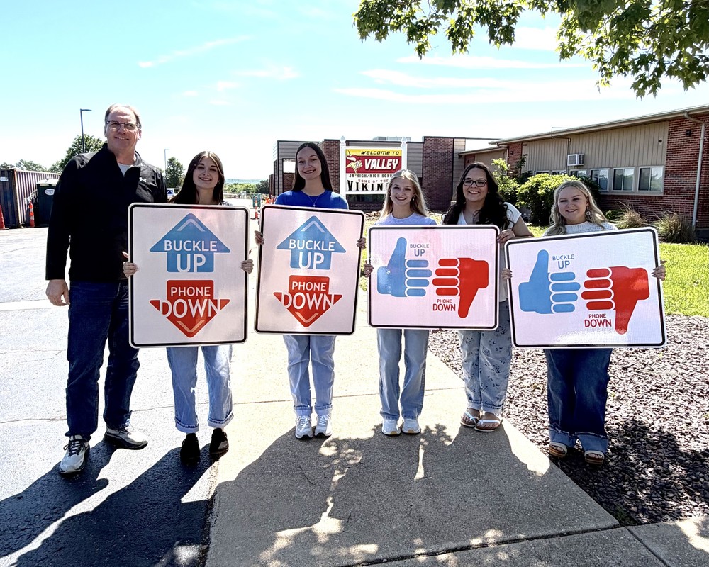 Students receiving Buckle Up Phone Down Signs for School District