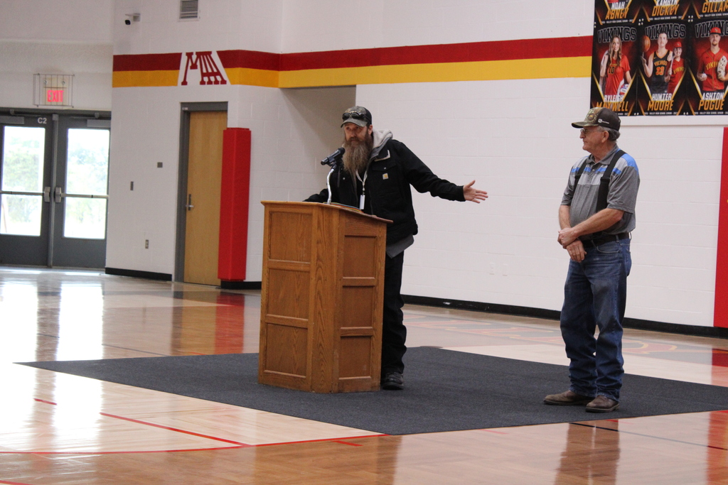 man speaking at podium to another man