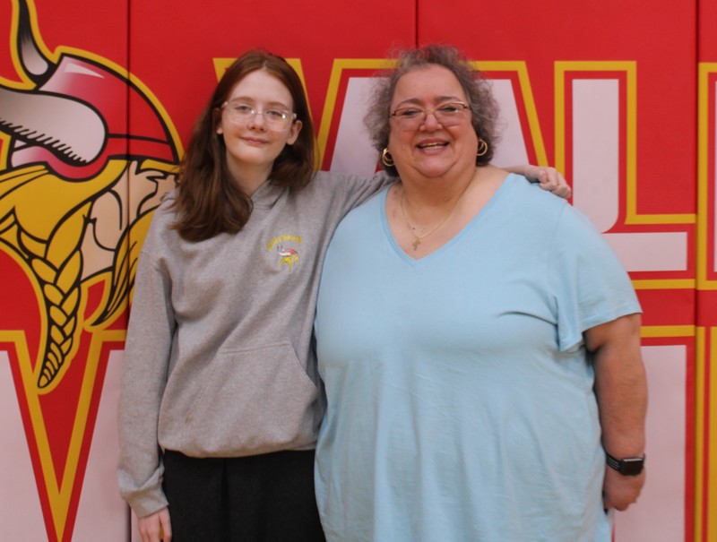 Student and teacher posing in front of wall