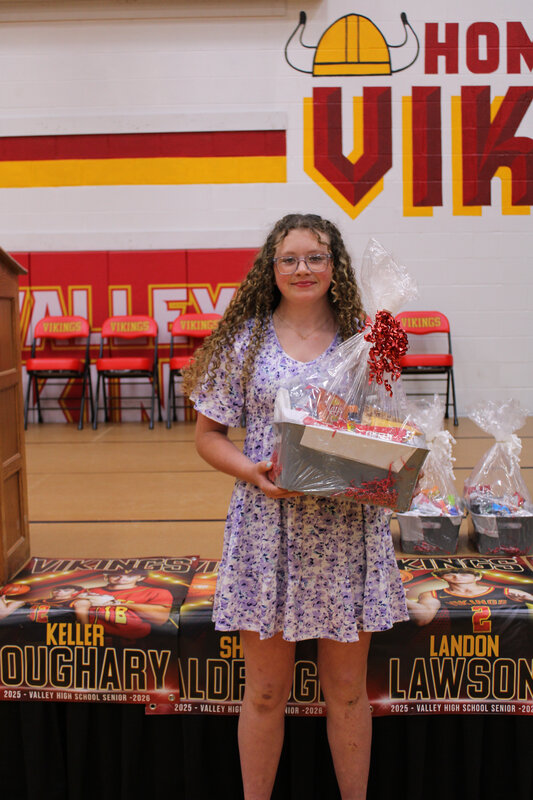 student holding basket in front of stage