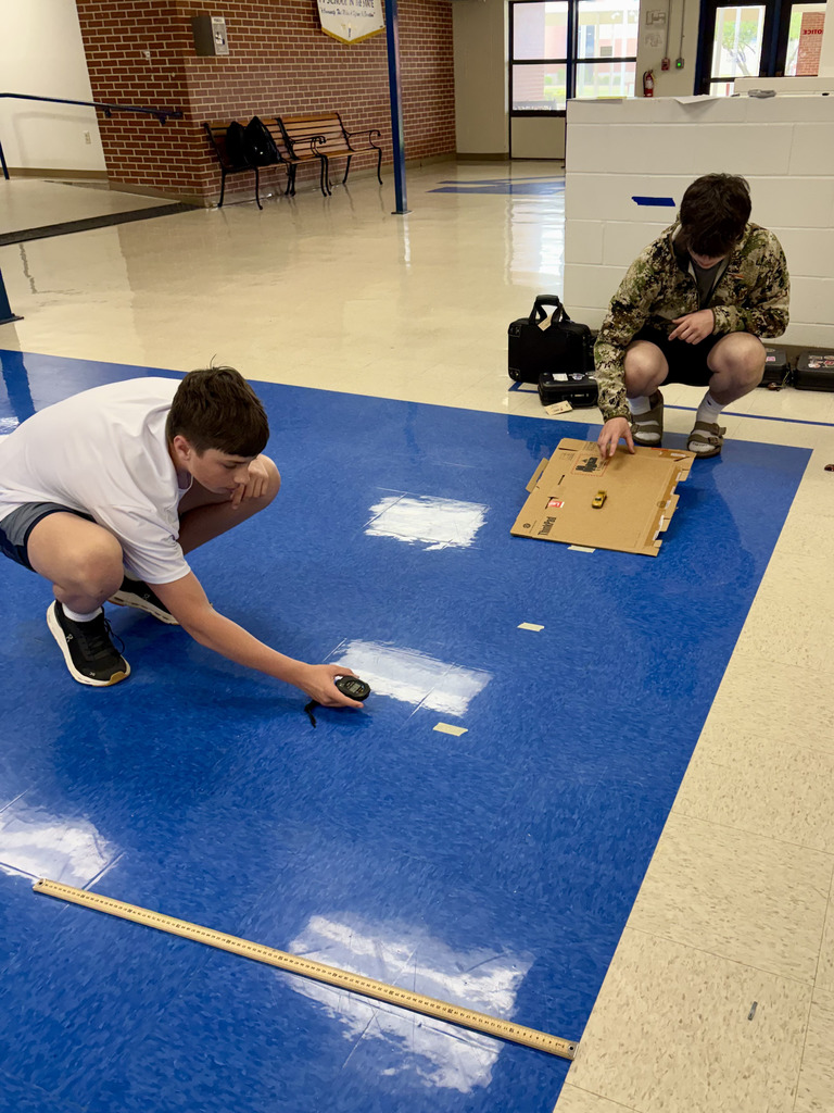 two boys measure distance of rolling cars