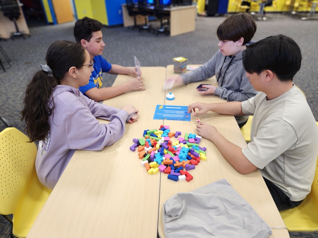 four students playing a game in the library