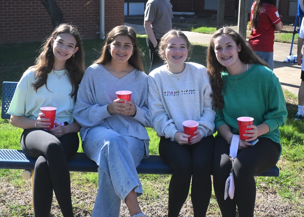 four girls outside on a bench holding drinks
