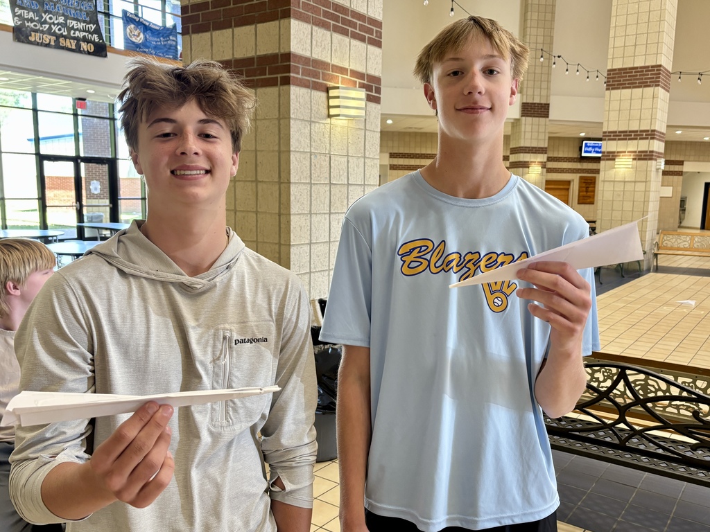 two boys holding their recently designed paper airplanes 