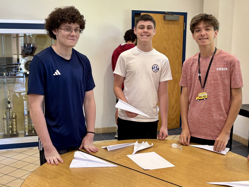 three students standing by round table