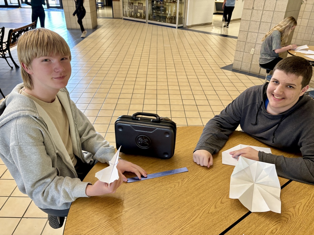 two boys with their paper airplanes at a table