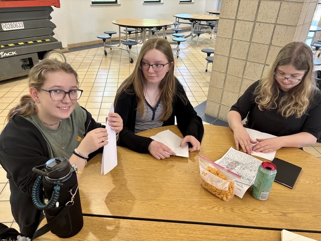 girls folding planes at a table