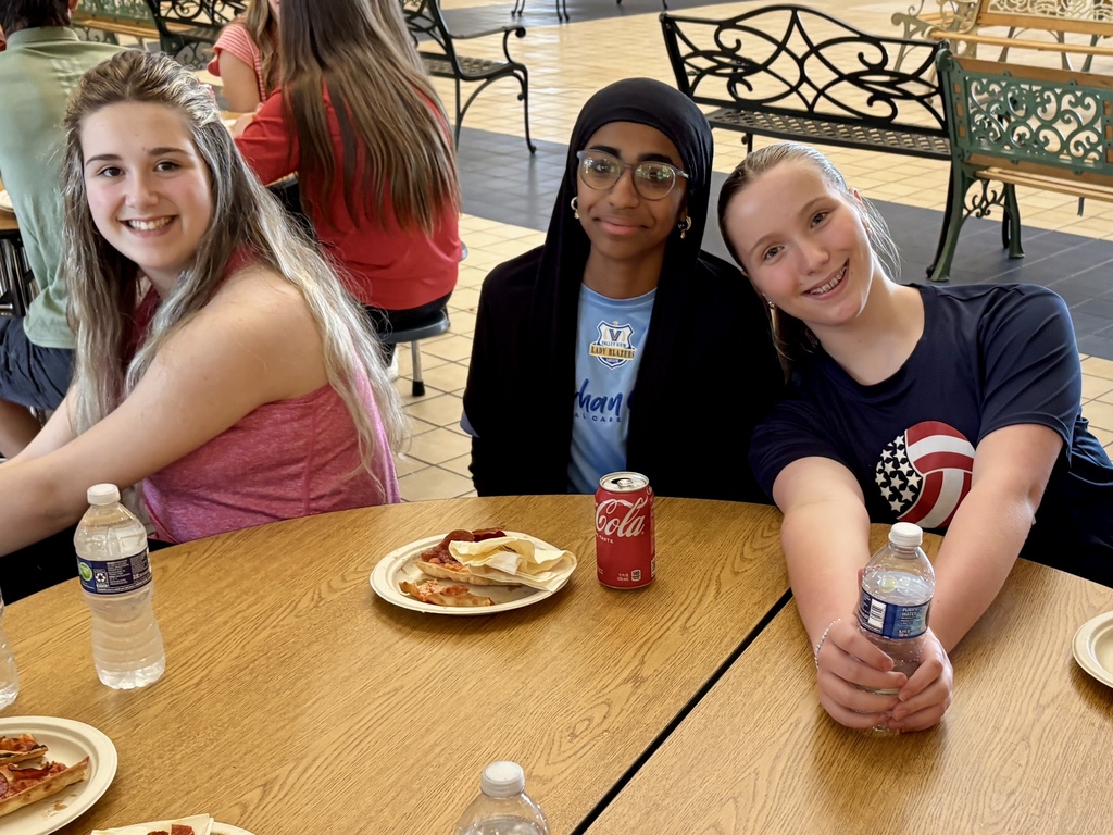 three girls seated together and smiling during lunch time