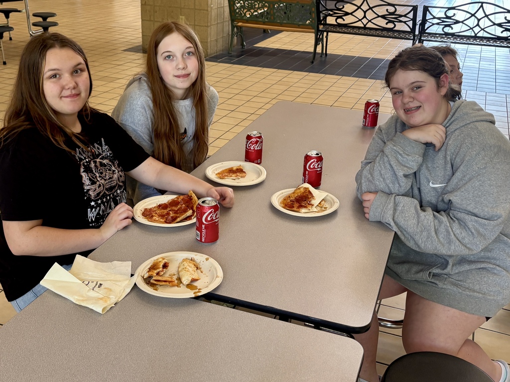 3 girls eating pizza at a table