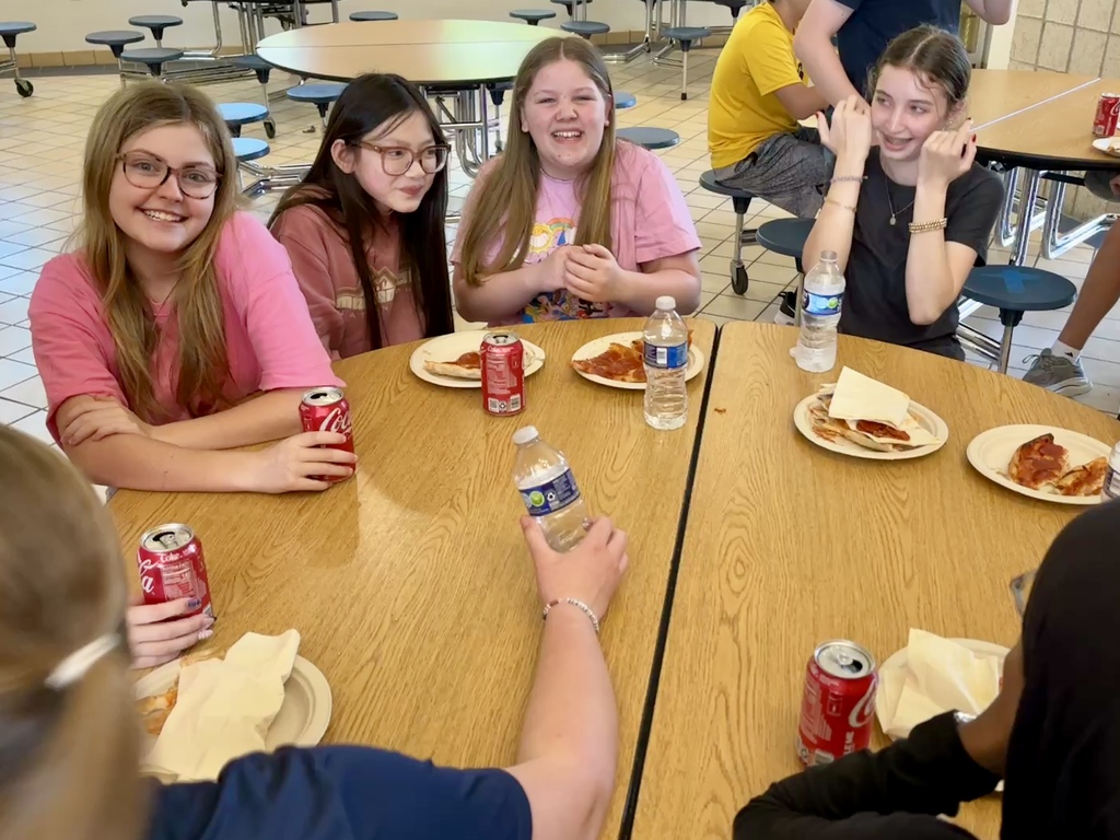 girls having a pizza lunch seated at a round table