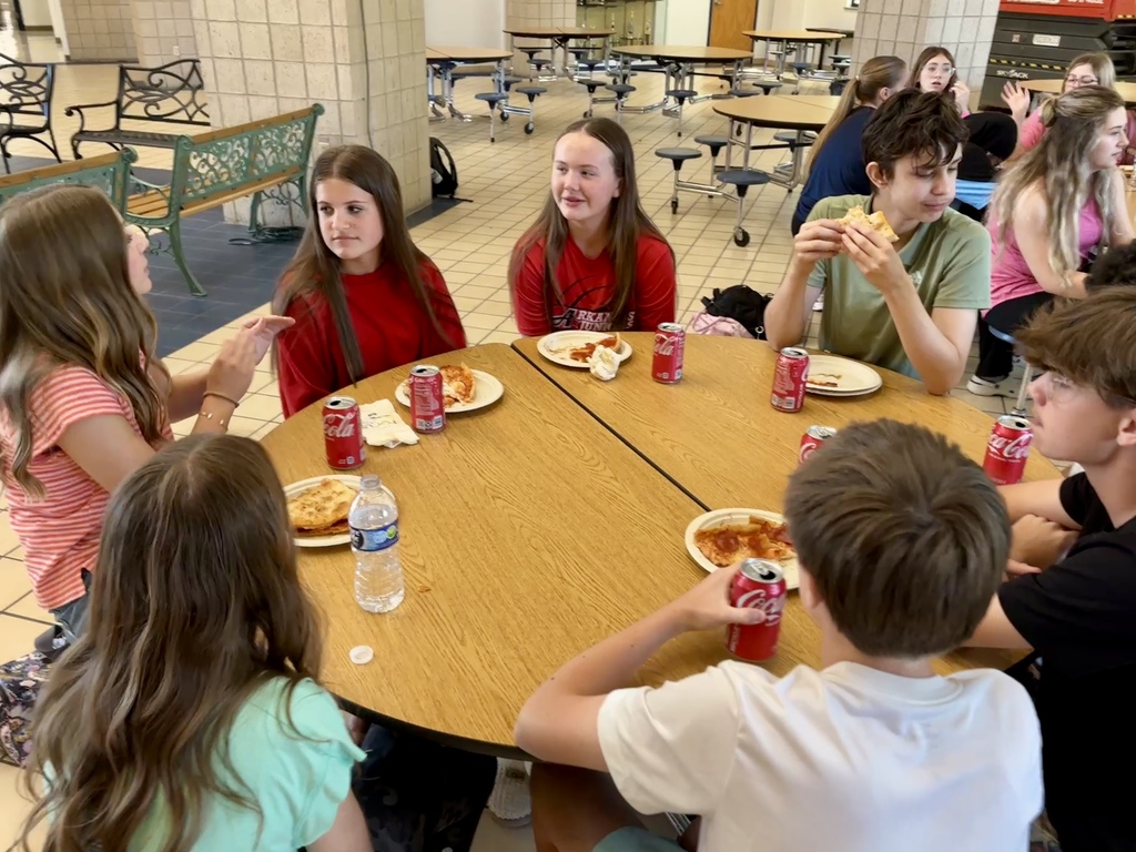 students seated around a round table having pizza lunch