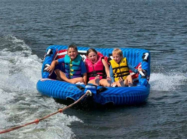 Children on a tube behind a boat.