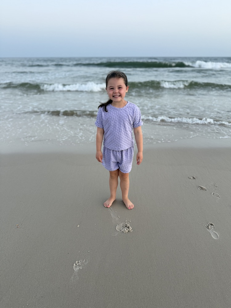 A little girl standing on the beach.