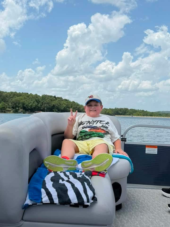 A little boy lounging on a boat in the lake.