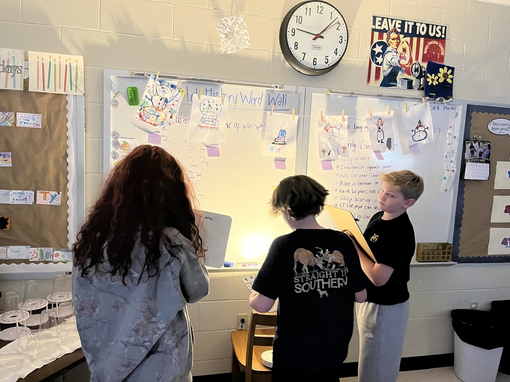 Three students touring the art work in Ms. McGowan's classroom