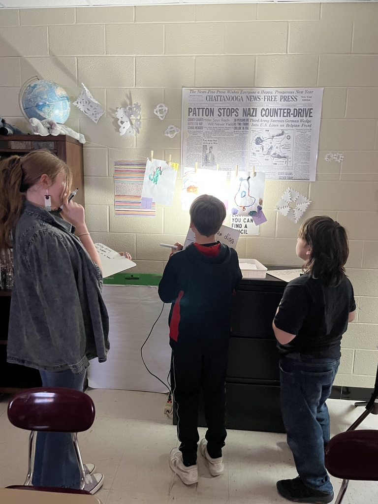 Three students touring the art work in Ms. McGowan's classroom