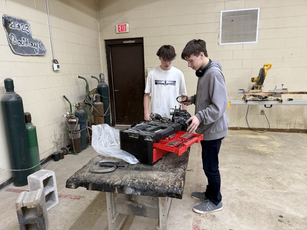 two students working together in a shop class on small engine repair