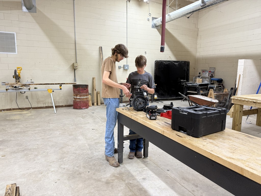 tow students working together in shop class on small engine repair