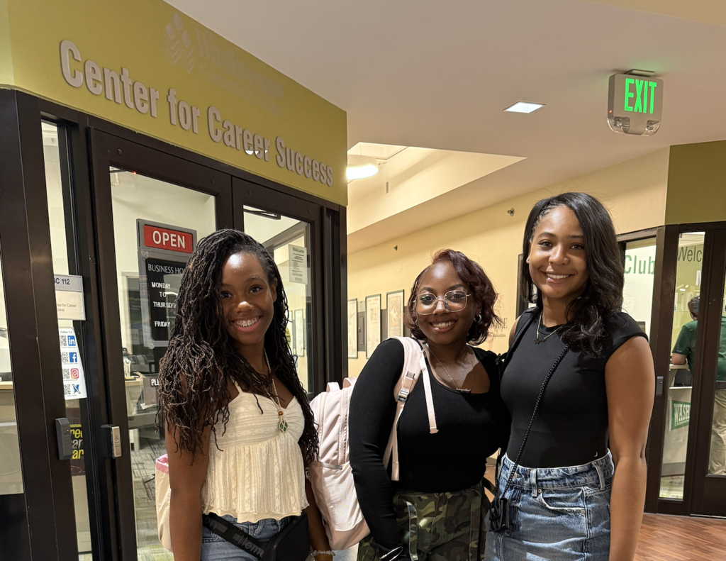 2 Early College students stand smiling in front of the center for career success
