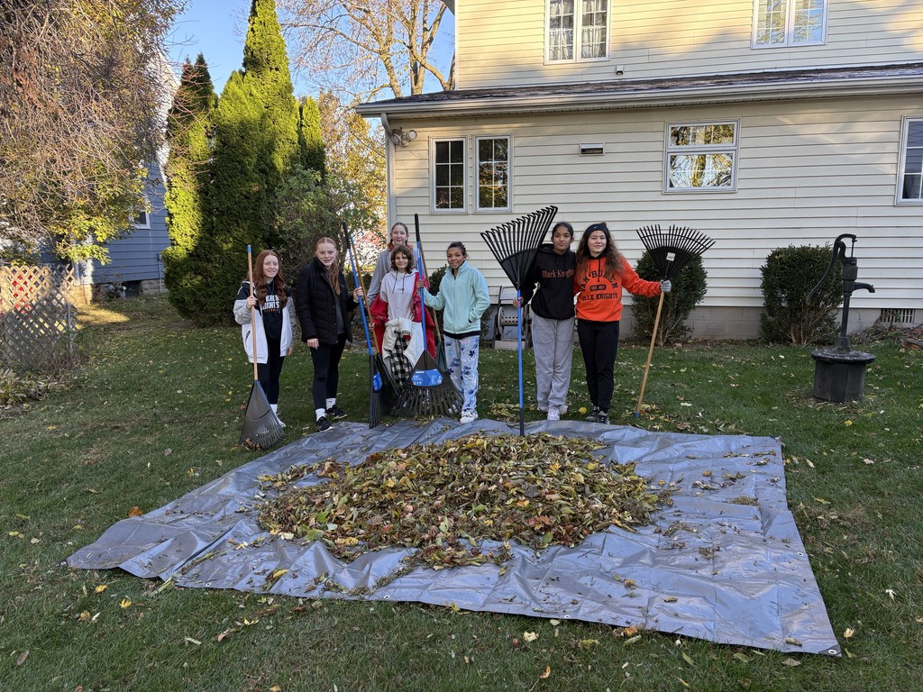 Group of students standing behind leaves on tarp