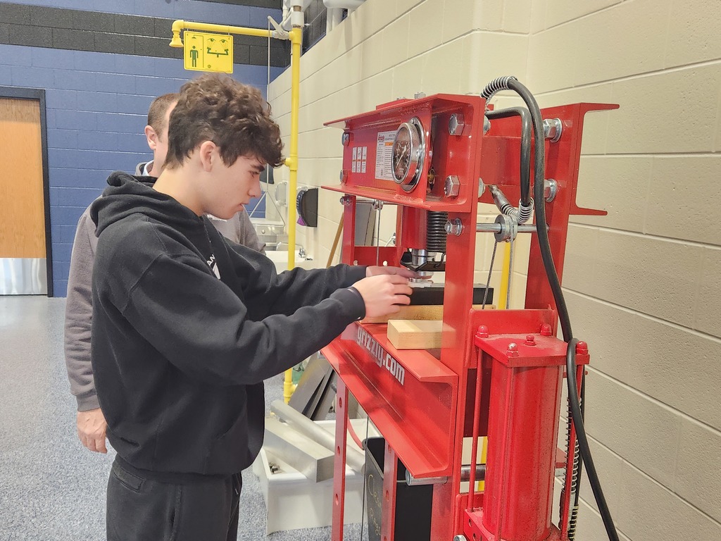 A student places his spinner into the press so he can push the bearing into it.