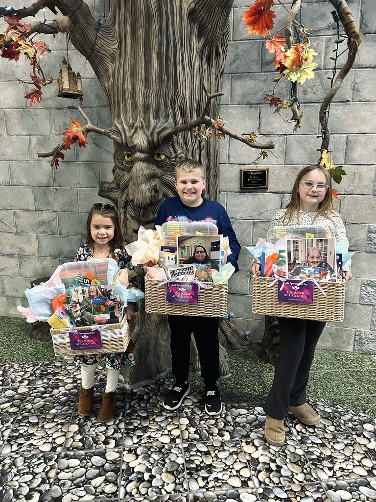Three elementary students that won and their prize baskets