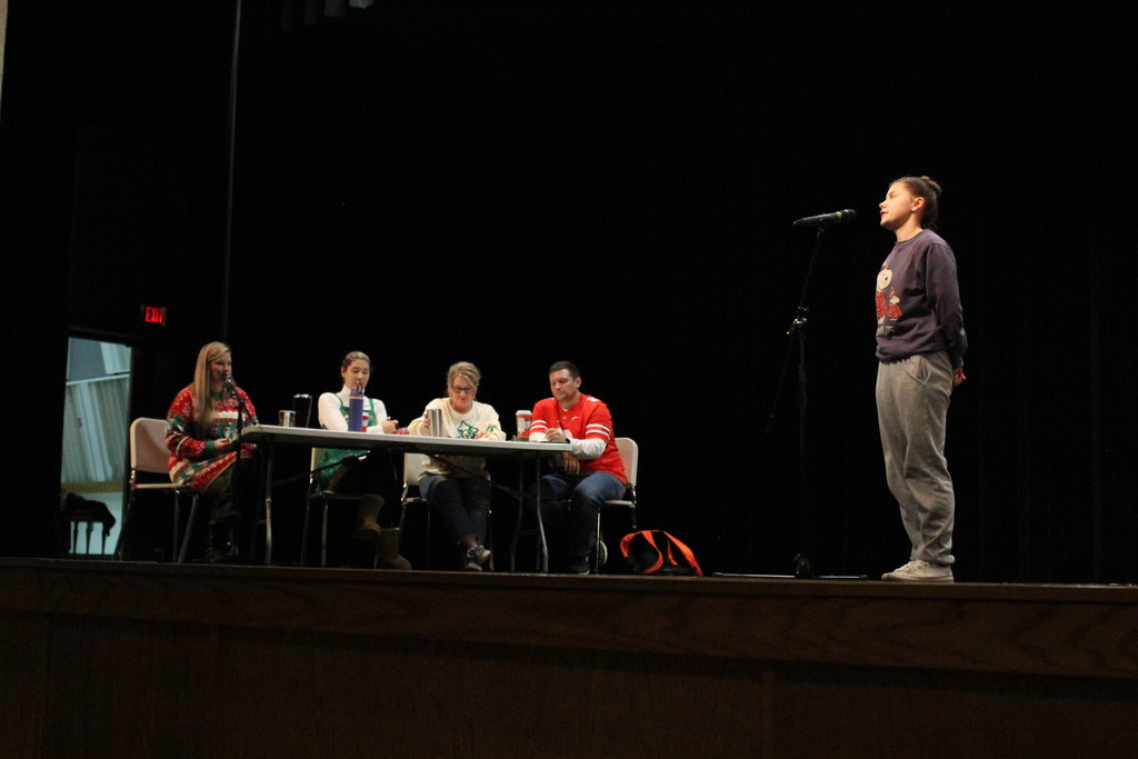 A participant spells a word while the judges confirm the spelling.