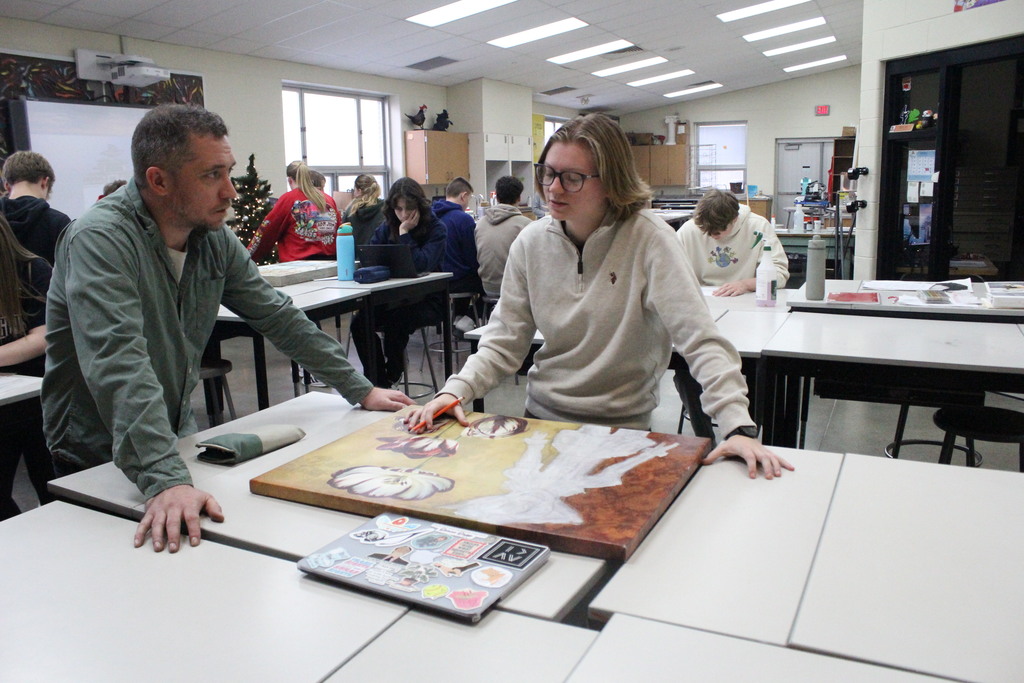 A high school art student confers with Mr. Frey regarding what she will be adding to her Habitat for Humanity artwork.