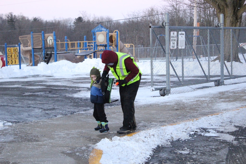 Ms. Stacy Sharp helps a student put on his backpack before heading into the building.