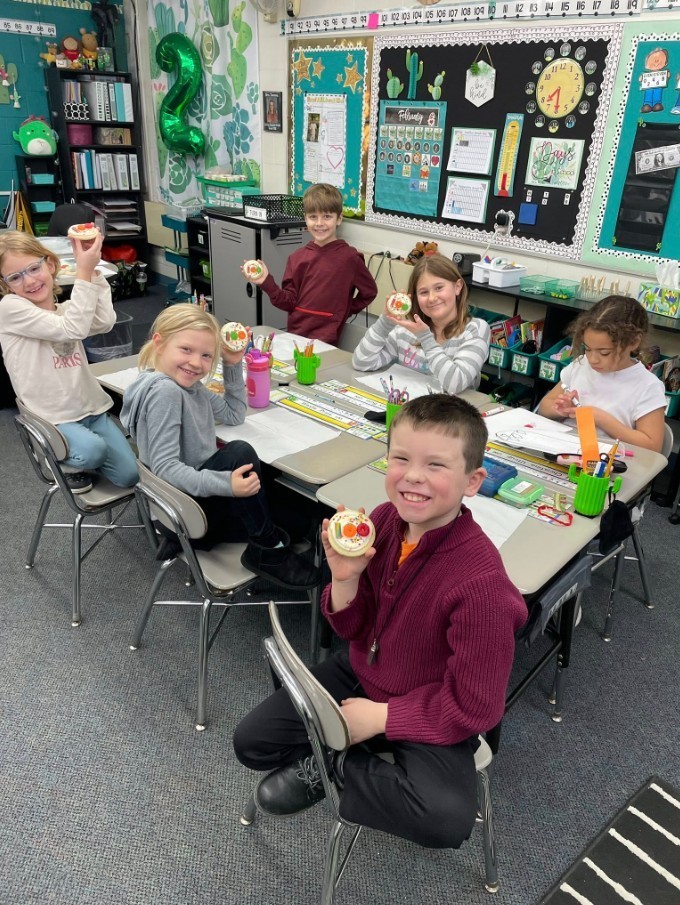 Students show their 100th day cookies before eating them.