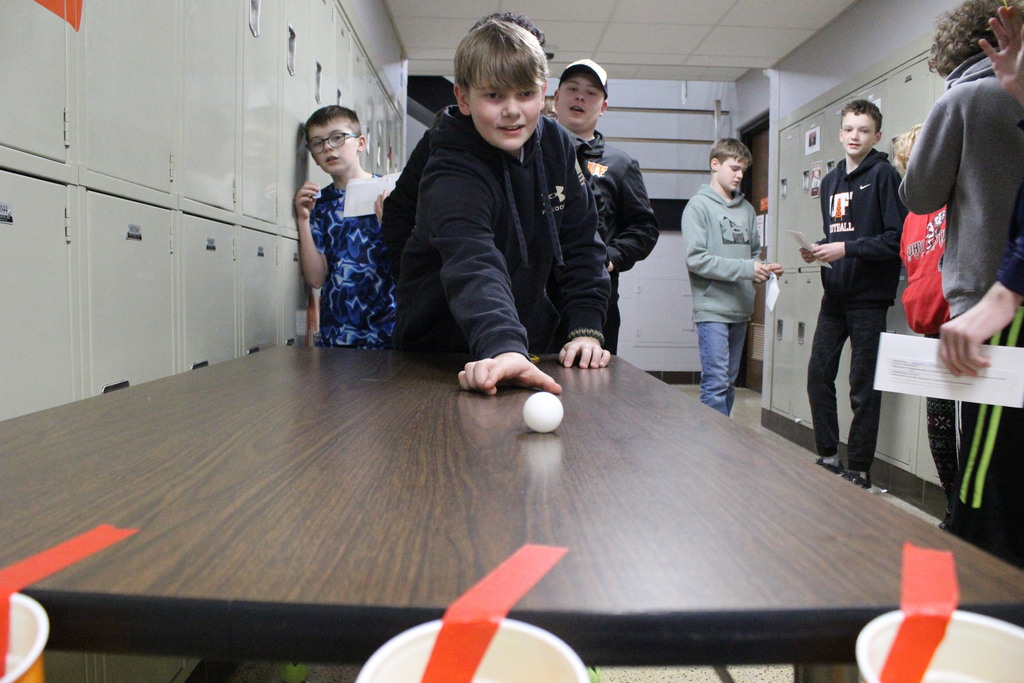 A student attempts to roll a ball across the table and into a cup to earn additional tickets.