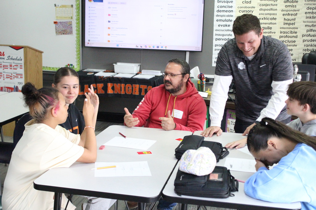 A family member works with students in an English class.