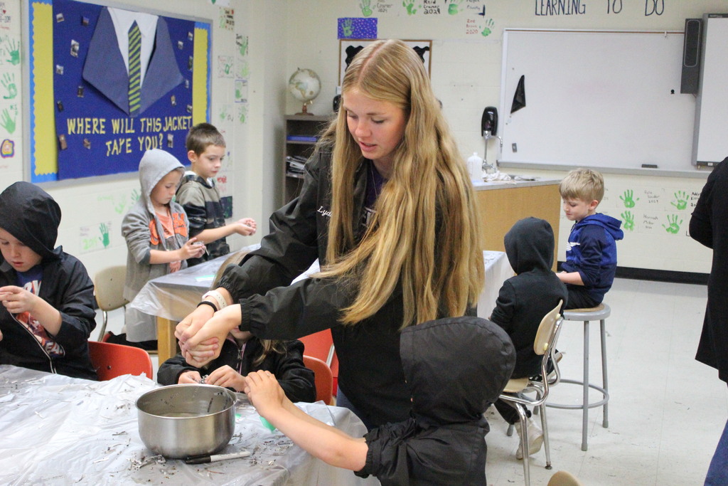 An agriculture education student helps an elementary student make a seed pod.