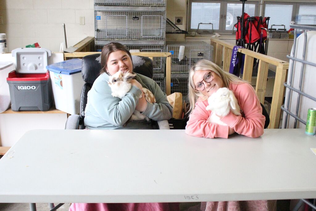 Agriculture education students hold rabbits so elementary students can see them.