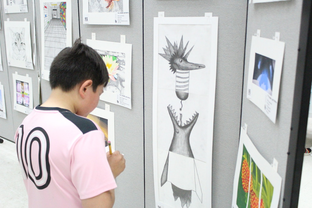 A student votes for his favorite piece of artwork at the art show.