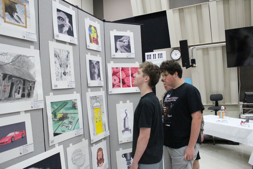 Students observe the artwork at the art show.