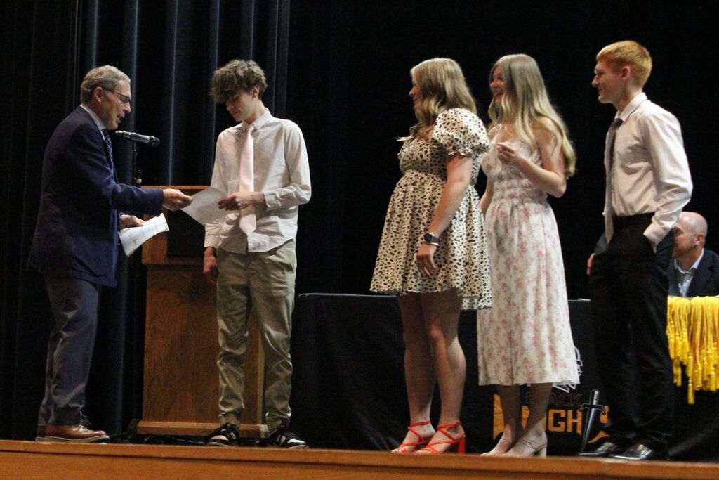 Mr. DeBolt, a substitute teacher at the school and part of the Children's Mentoring Connection board, hands out the CMC scholarships.