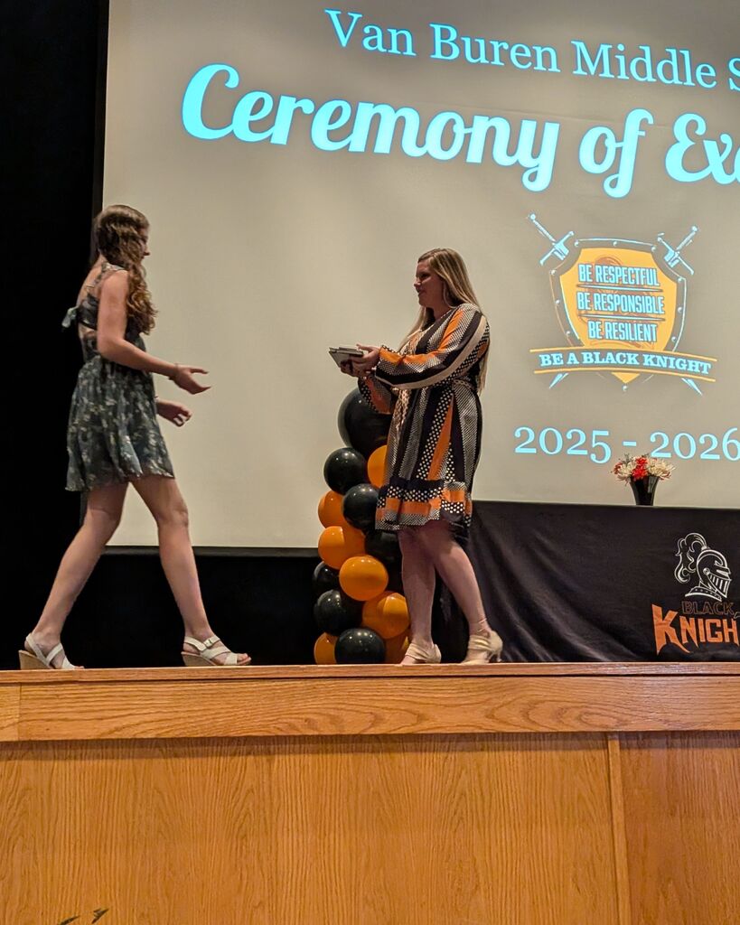 A middle school student receives an award from Mrs. Barrett.