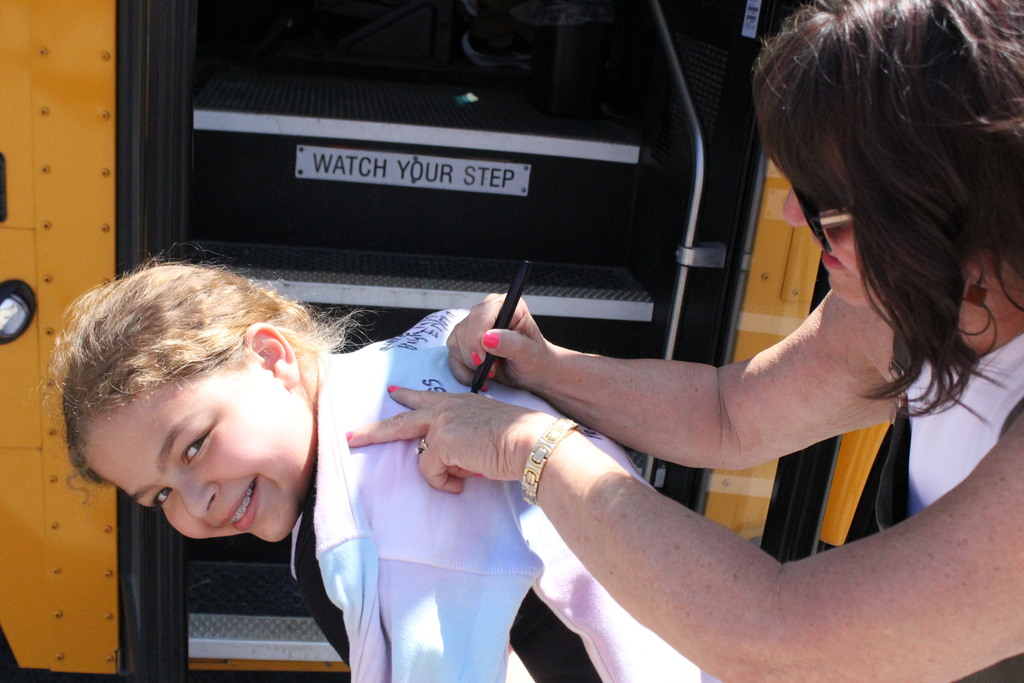 A student participates in a last-day-of-school ritual - having everyone sign her shirt.