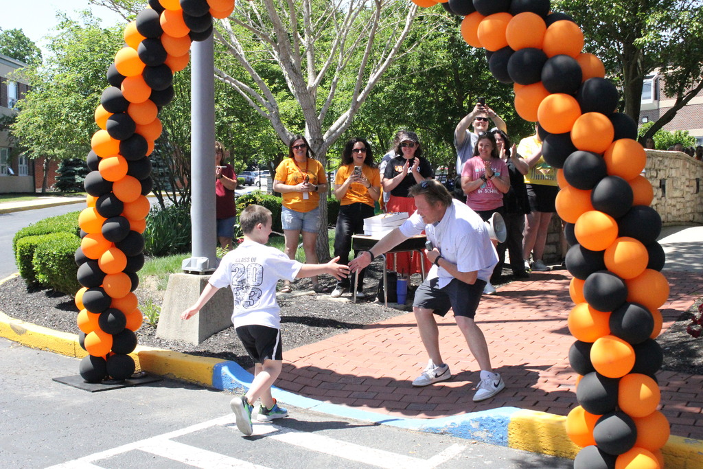 A fifth grader receives congratulations from Mr. Newcomer before crossing the bridge.