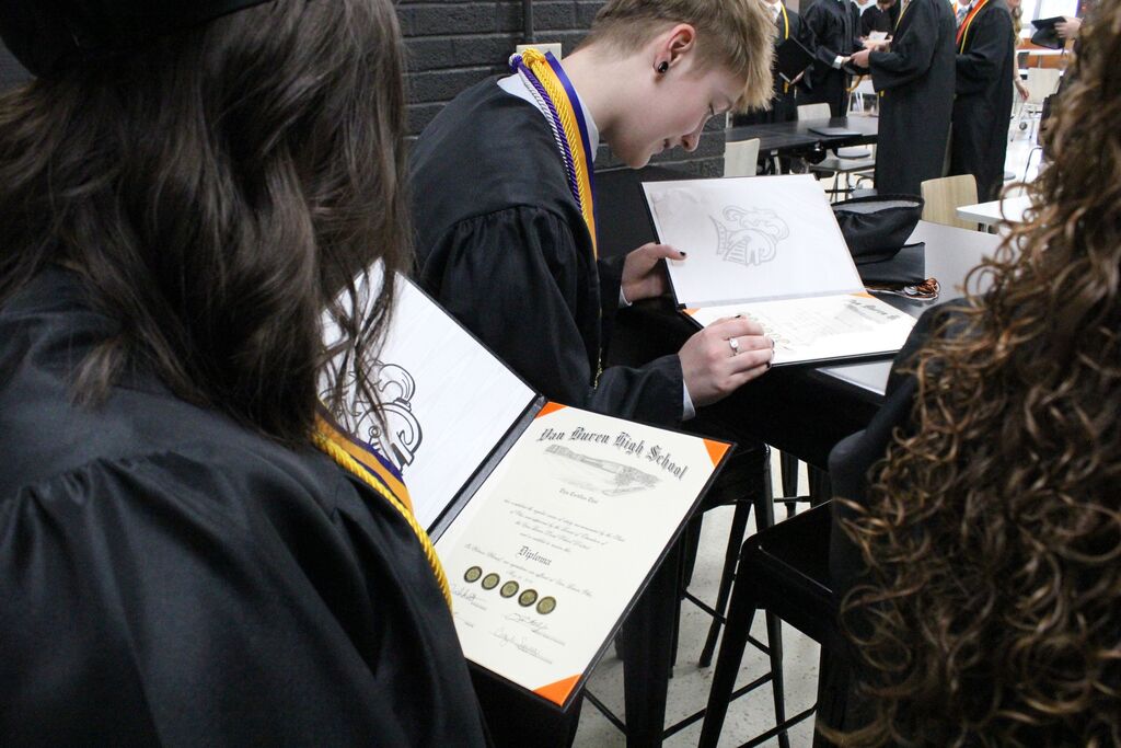 Students inspect their diplomas after the ceremony.