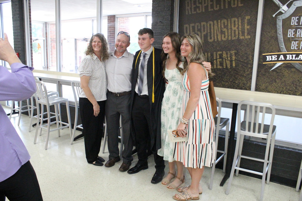 A family takes a picture with a graduate after the ceremony.